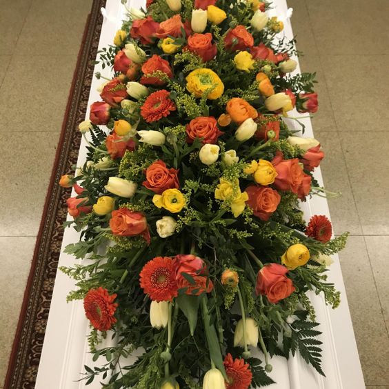 Stor bårebukett med gule, røde, og oransje blomster