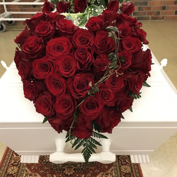 Røde roser formet som hjerte på hvit kiste